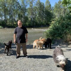A man wearing a black t-shirt with four dogs